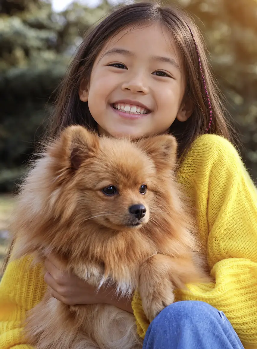 Young girl cuddling her Pomeranian during a happy moment outdoors