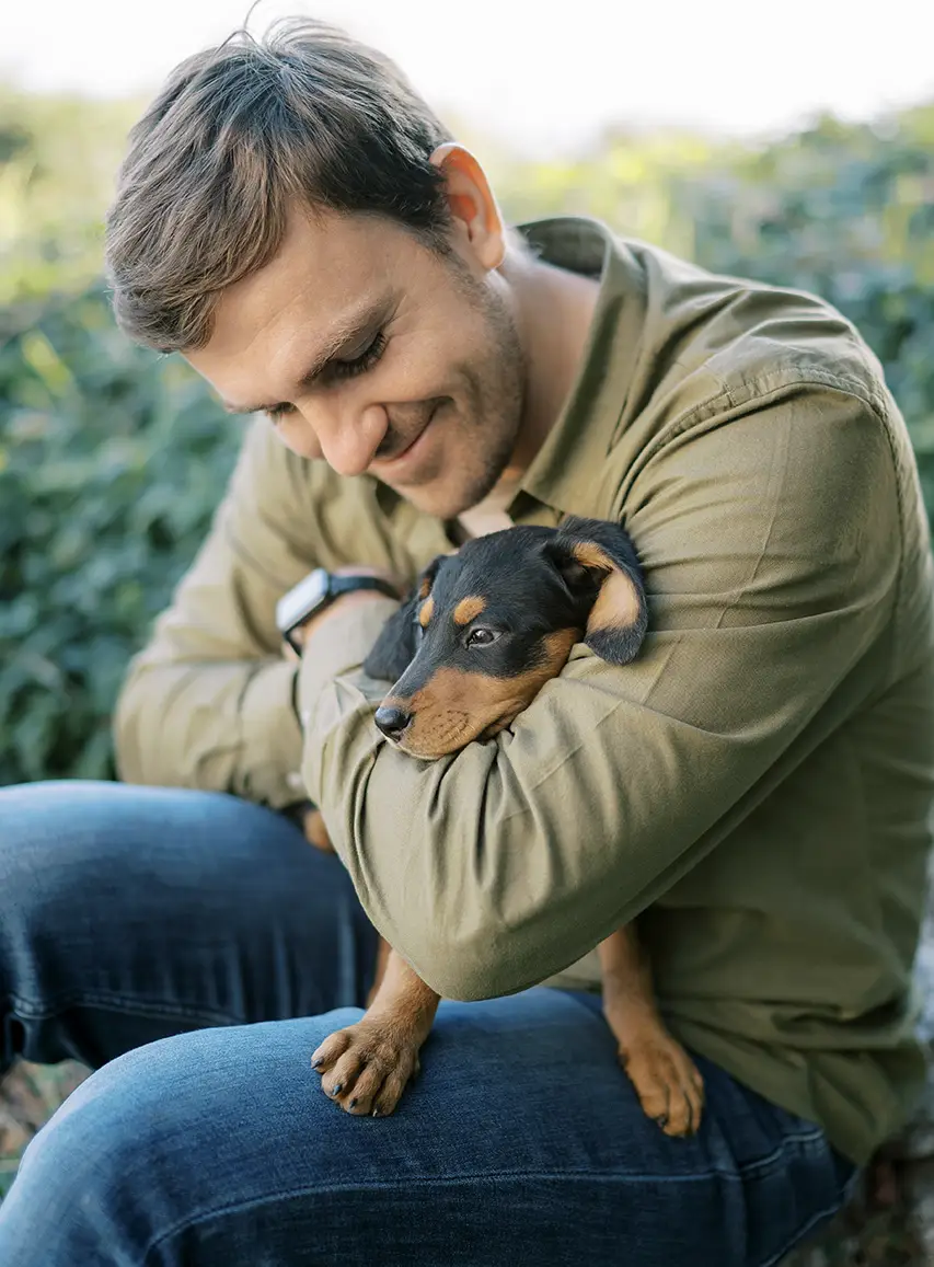 Man cuddling his dog outdoors as part of a daily dog wellness routine