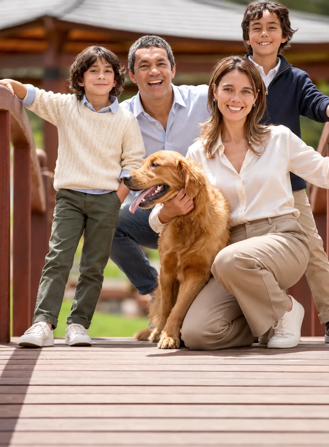 Family with two children posing outdoors with their Golden Retriever